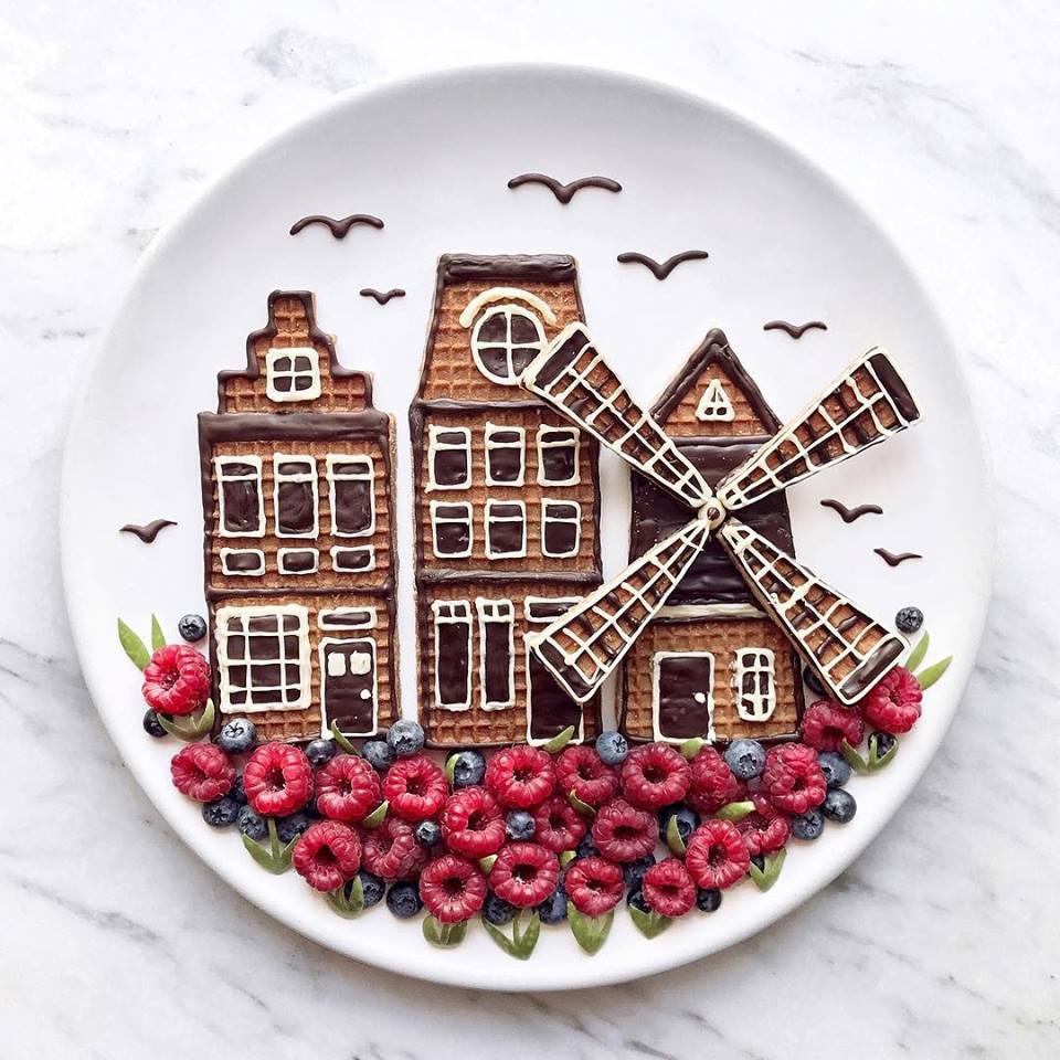 Paesaggio di casette e mulino a vento realizzato con biscotti, cioccolato e frutti di bosco